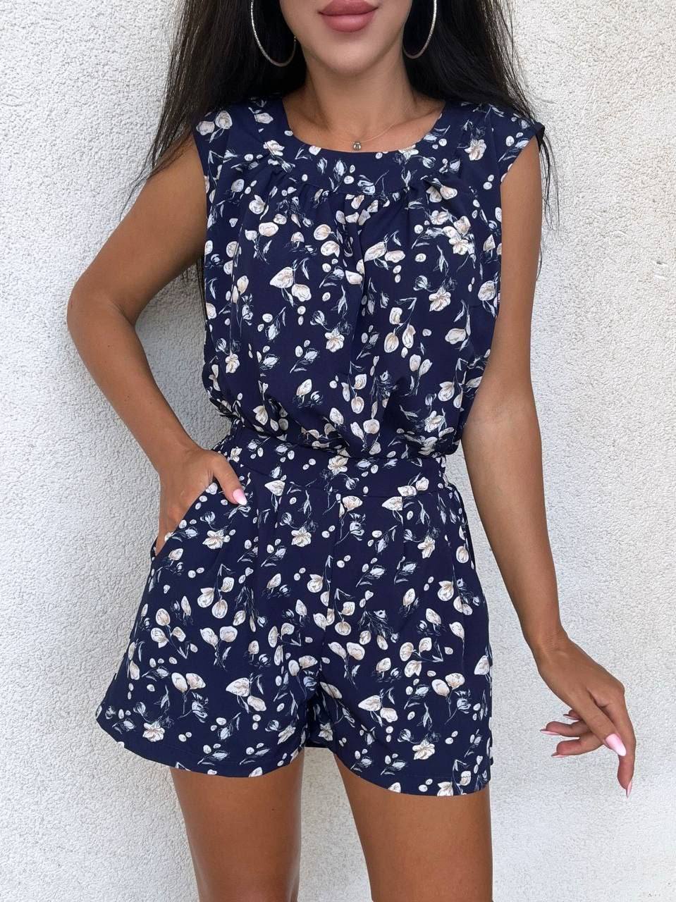 Woman wearing a navy blue floral romper against a white background