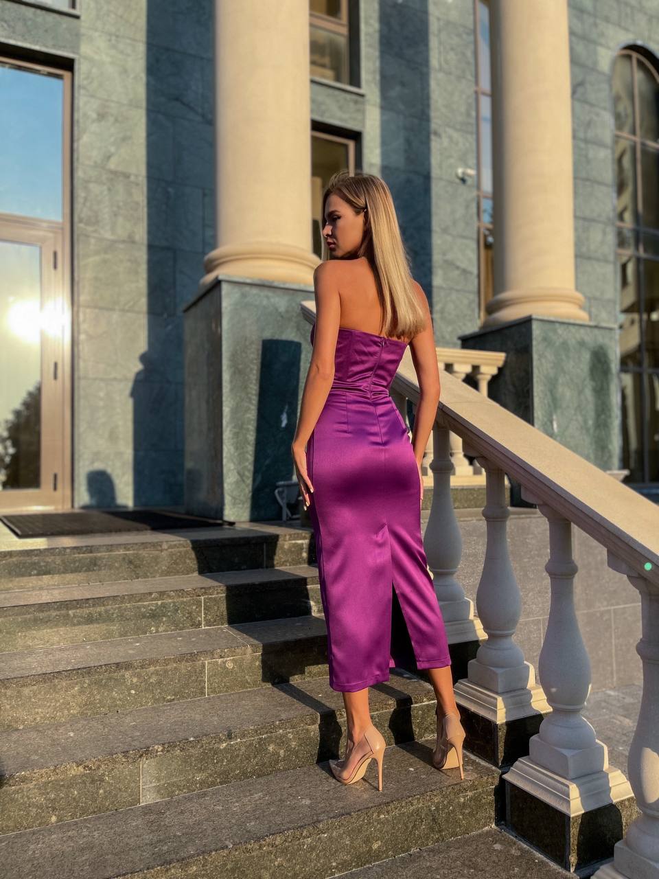 Woman in a purple dress standing on steps in front of a classical building