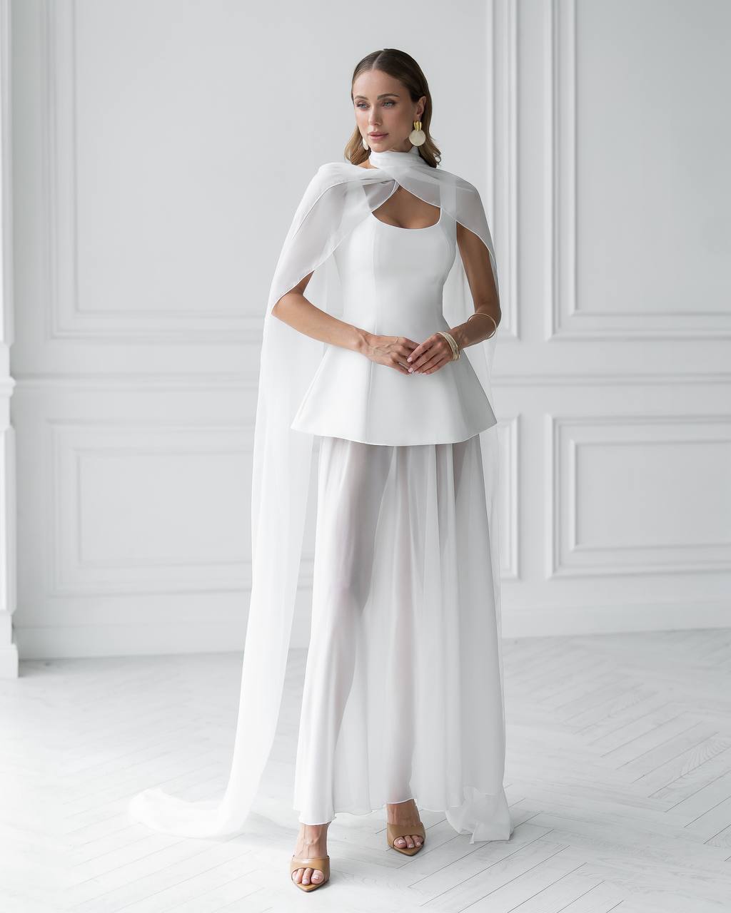 Woman wearing a white outfit with a cape against a white background
