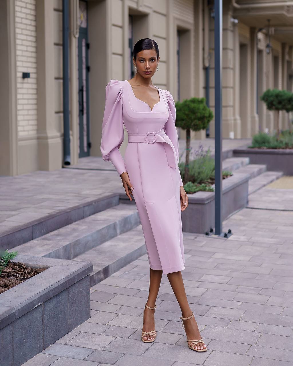 Woman in a pink dress standing on a city street.