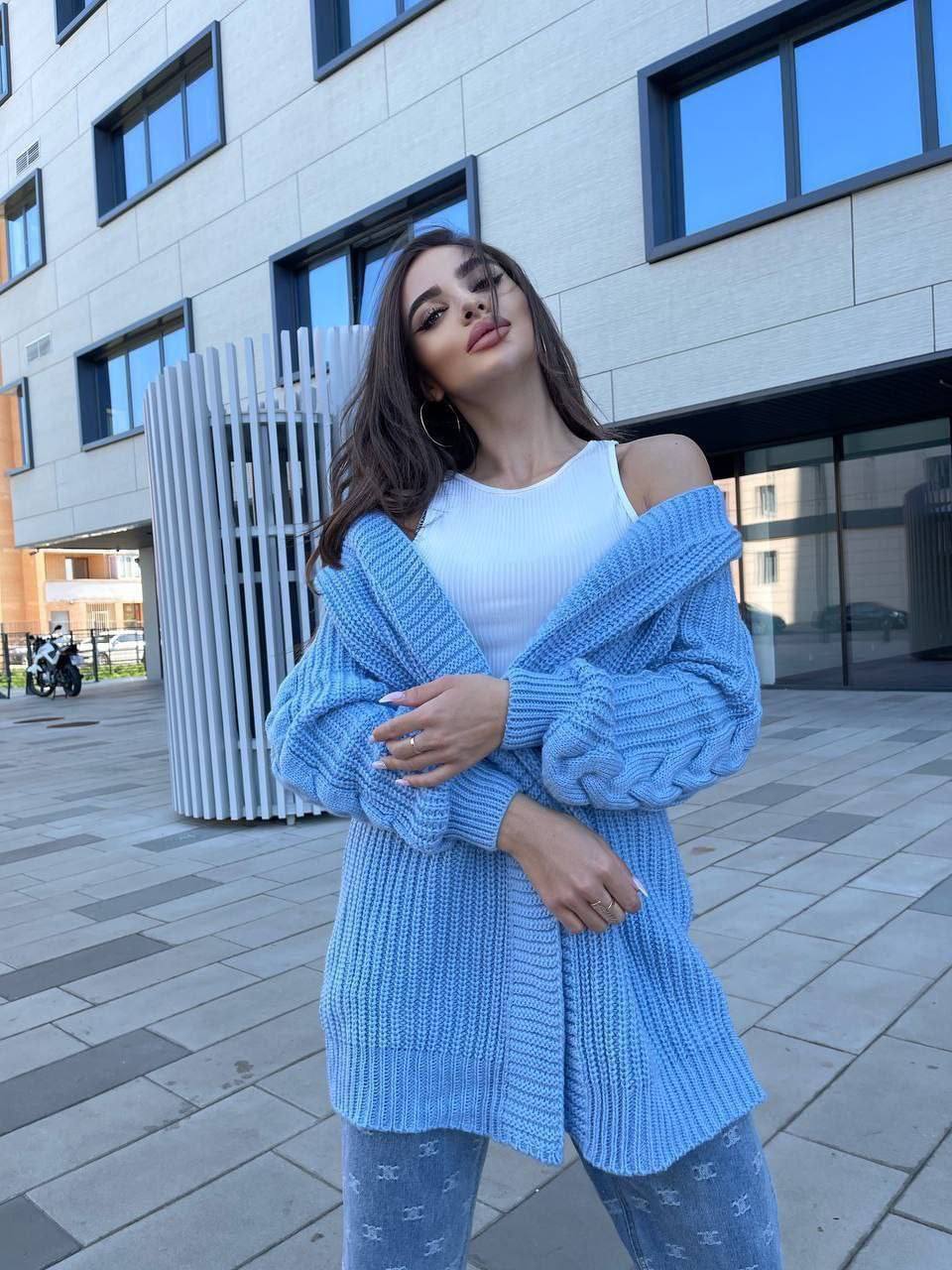 Woman wearing a blue knitted cardigan and white top in an urban setting