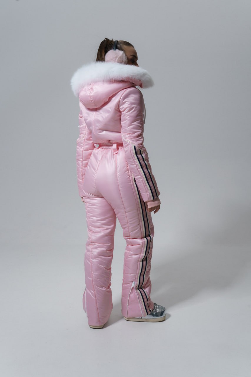 Person wearing a pink puffer suit with fur hood on a white background