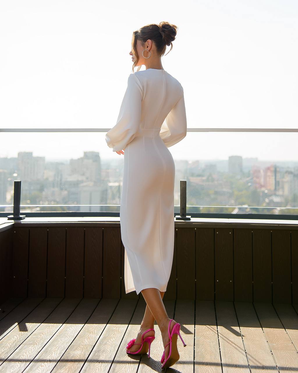 Woman in a white dress standing on a rooftop with a cityscape view