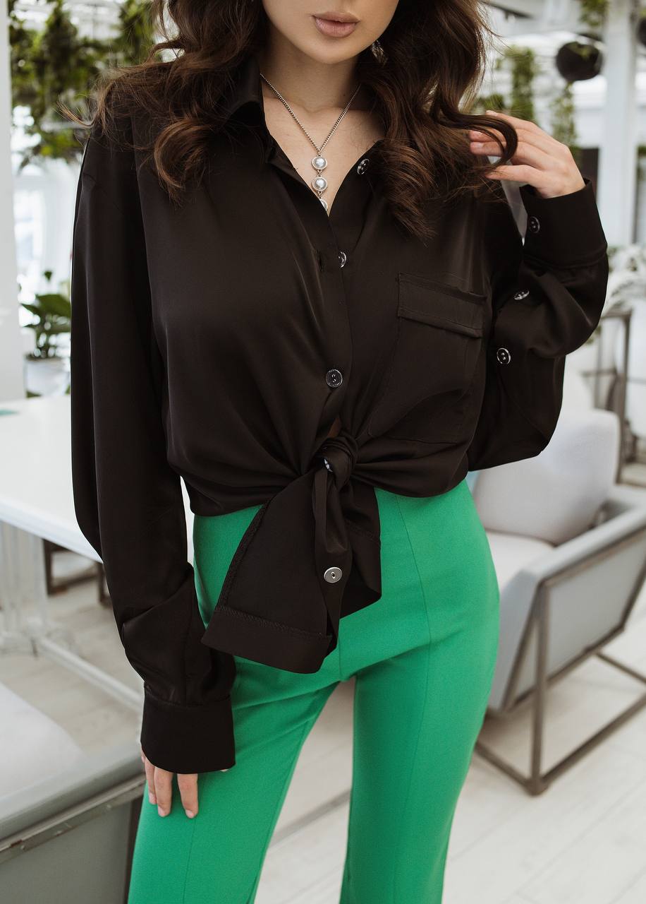 Woman wearing a black blouse and green pants in an outdoor setting