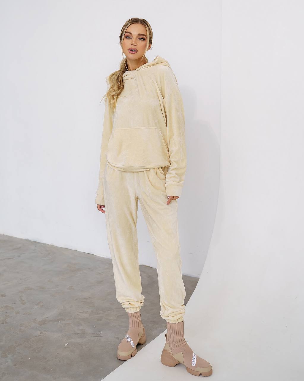 Woman wearing a beige tracksuit against a white background