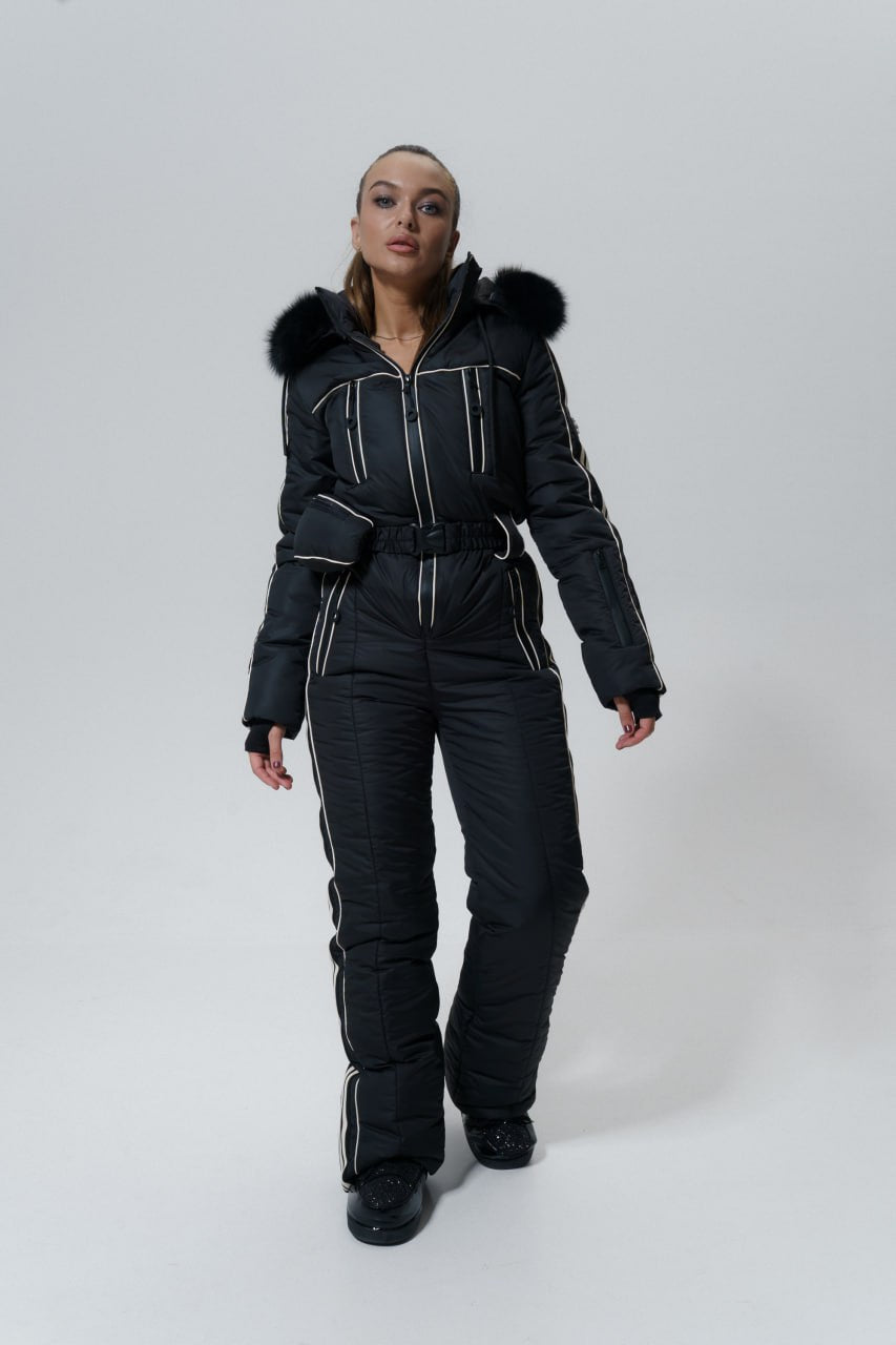 Person wearing a black snowsuit with fur hood on a white background