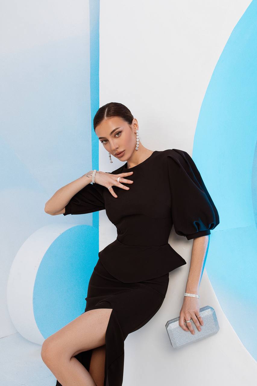 Woman in a black dress posing against a modern, abstract background