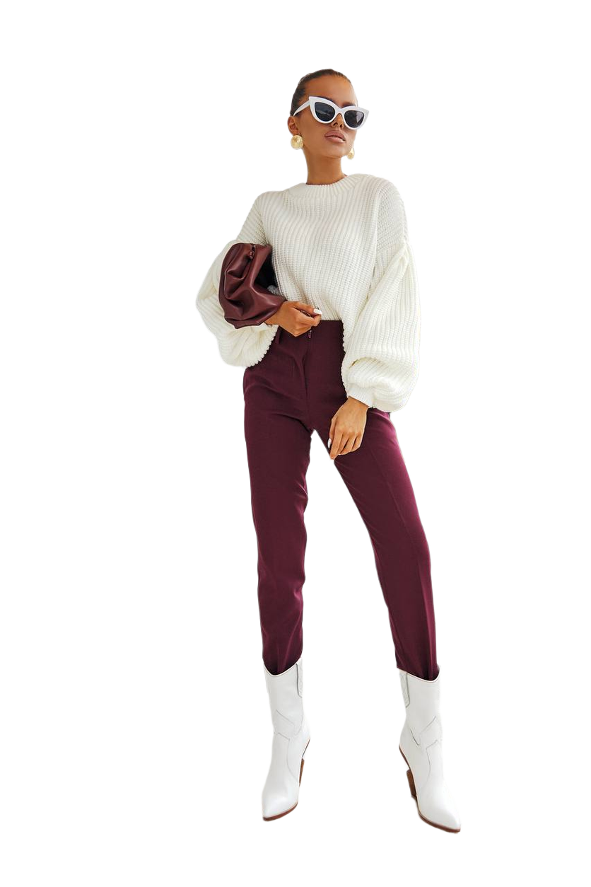 Woman wearing a white sweater, burgundy pants, and white boots on a white background