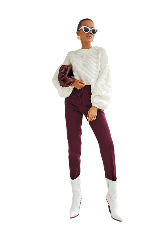 Woman wearing a white sweater, burgundy pants, and white boots on a white background