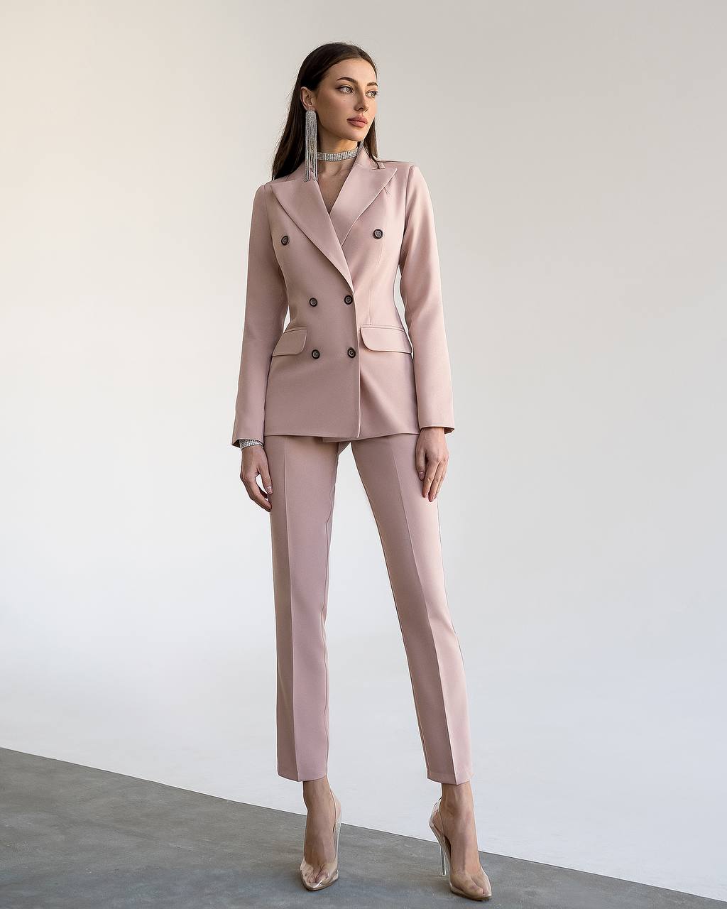 Woman wearing a pink suit against a plain background