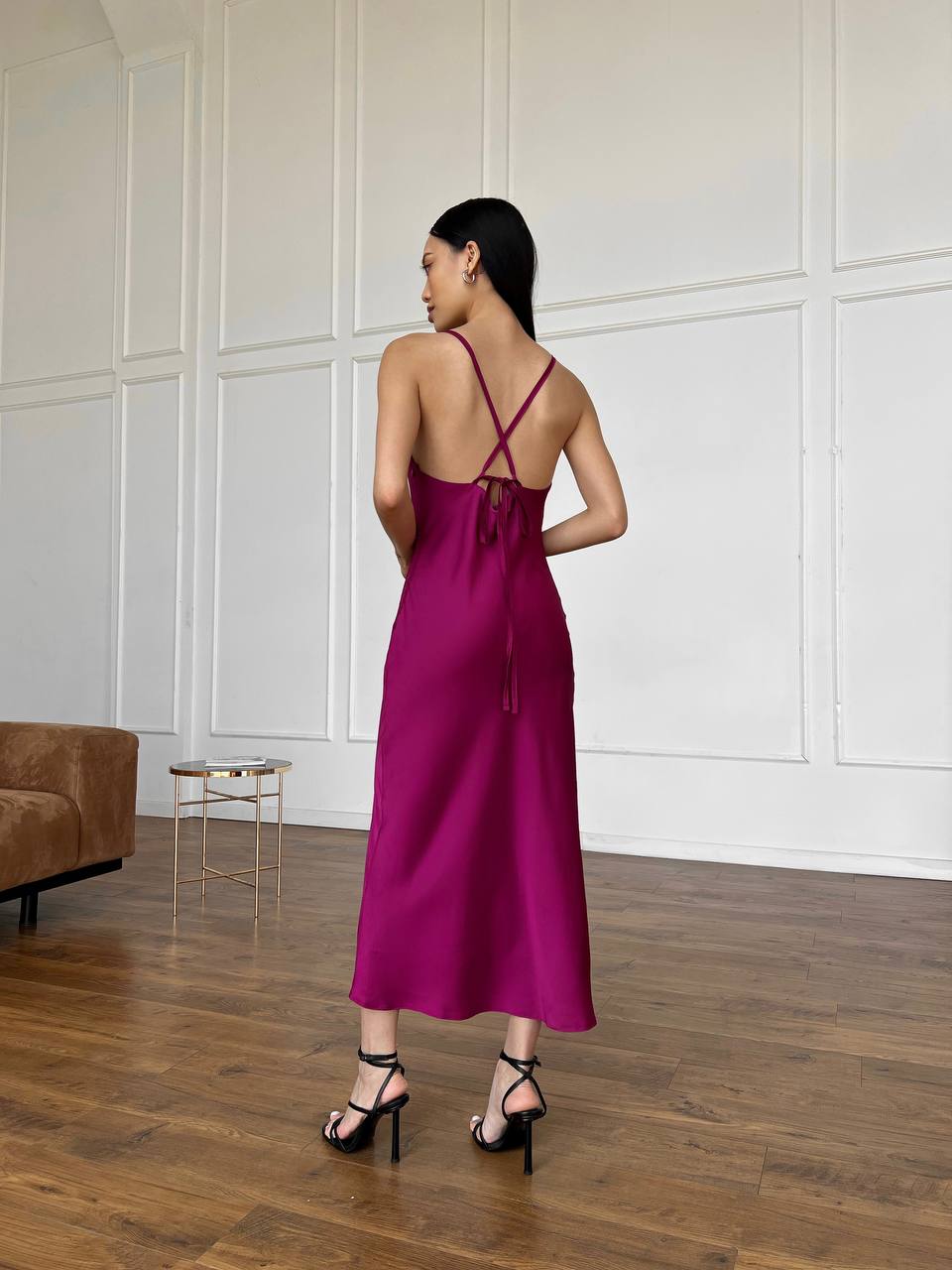 Woman wearing a magenta slip dress in a minimalistic room.