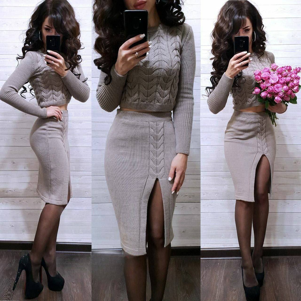 Woman wearing a beige cable knit sweater and skirt set, holding pink flowers.