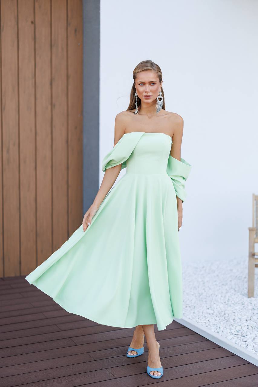 Woman wearing a light green strapless dress with ruffled sleeves on a wooden deck.