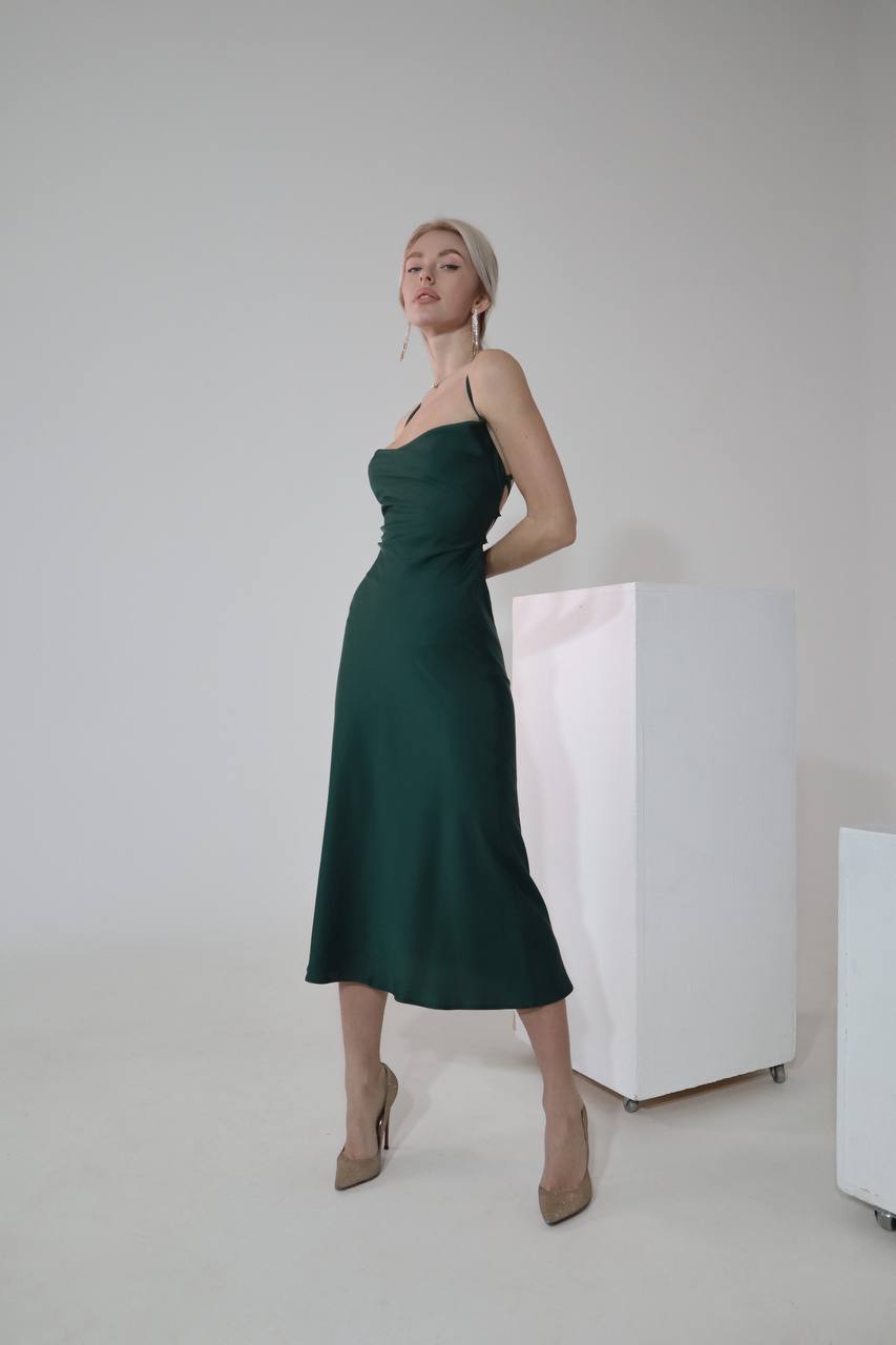 Woman wearing a green dress standing against a plain background