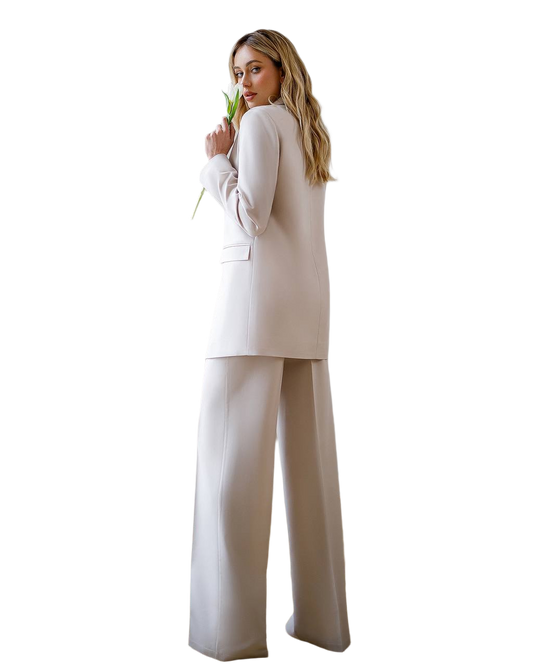 Woman wearing a beige suit holding a flower on a white background