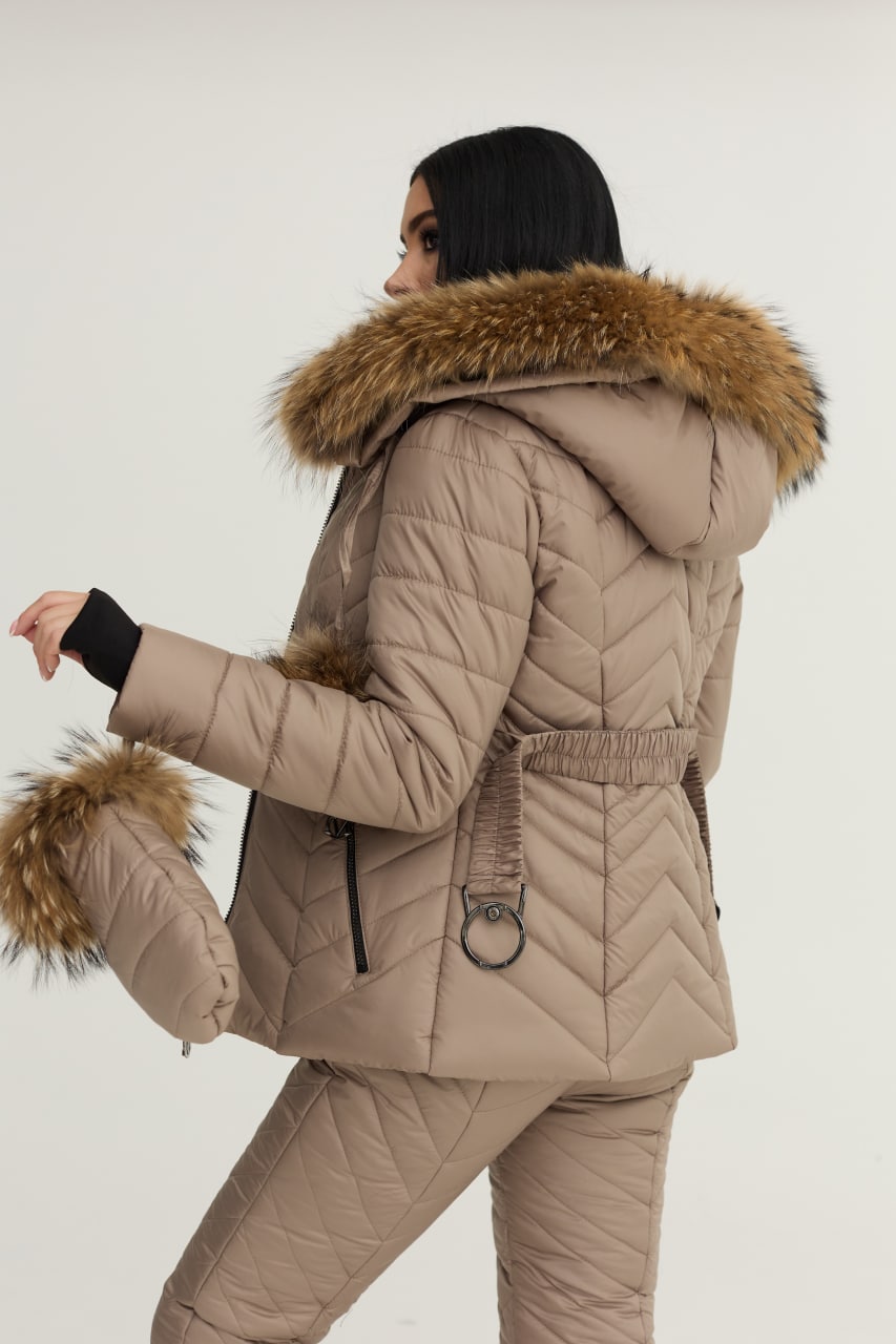Person wearing a beige puffer coat with fur hood and cuffs on a white background