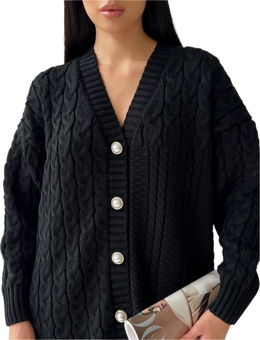 Black cable knit cardigan with silver buttons worn by a person on a white background