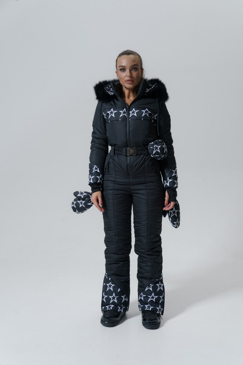 Person wearing a black snowsuit with star patterns on a white background