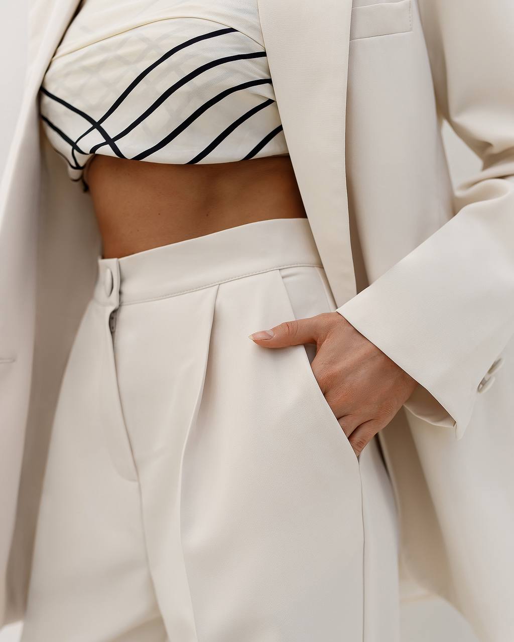 Person wearing a white outfit with a striped top and beige coat.