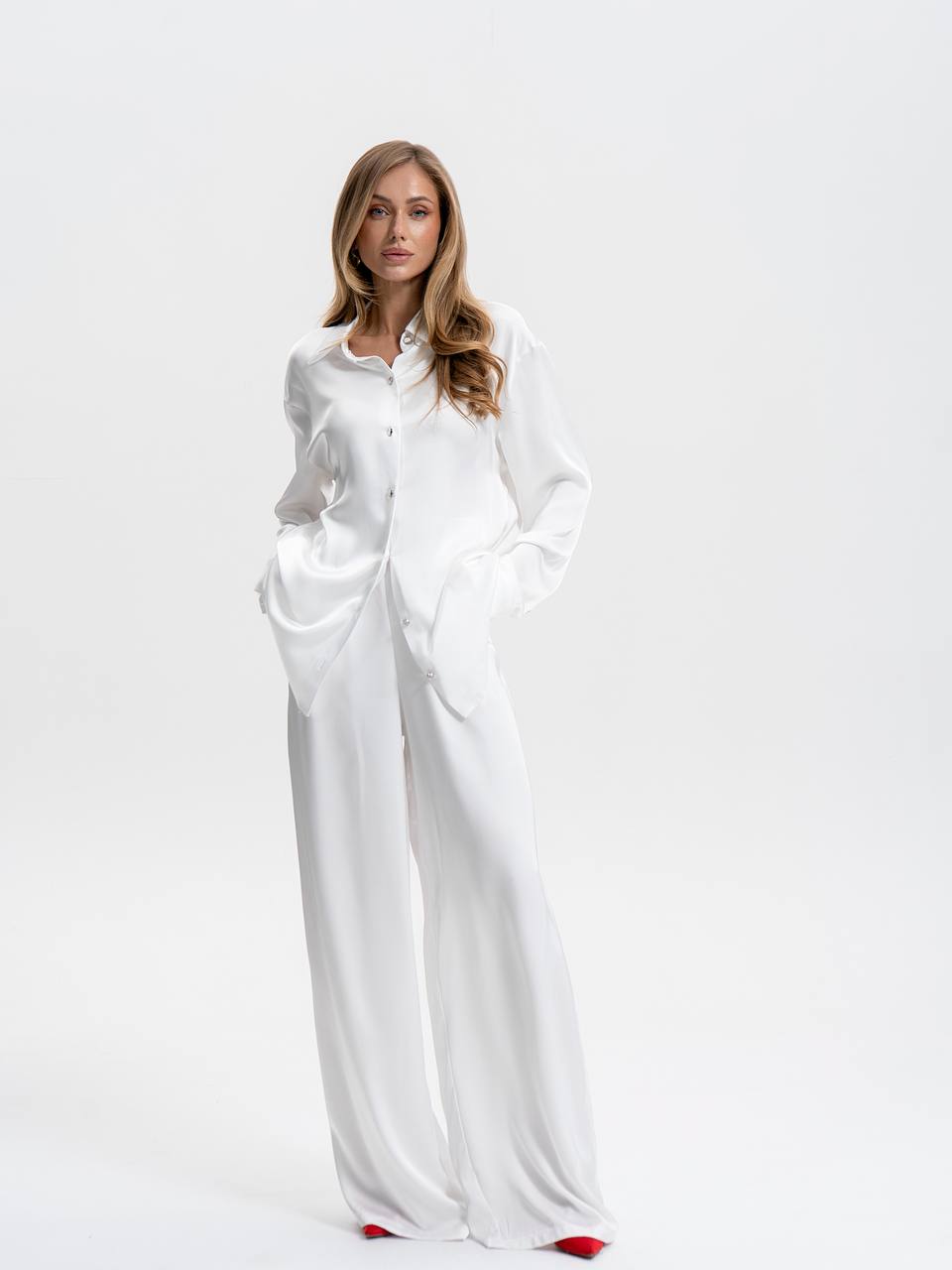 Woman wearing a long white dress with a high collar on a white background