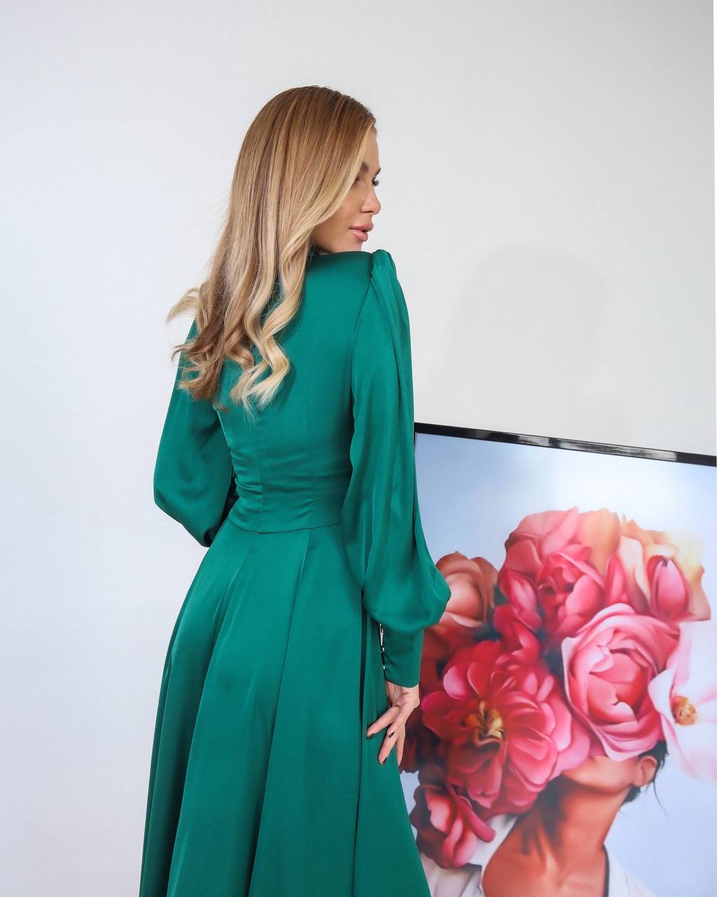 Woman in a green dress standing in front of a floral painting