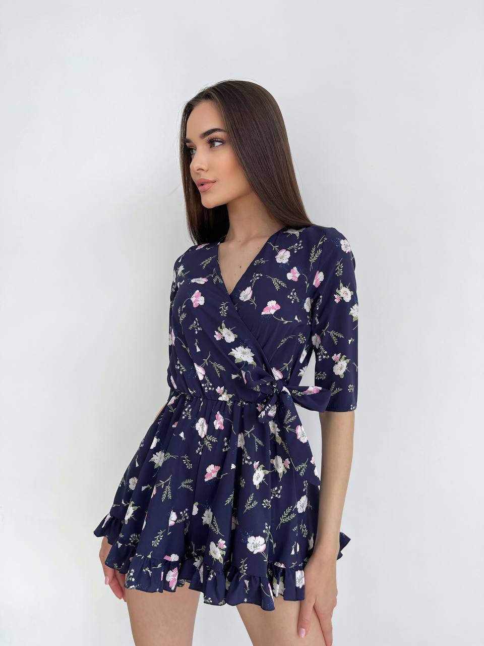 Woman wearing a navy floral dress against a white background