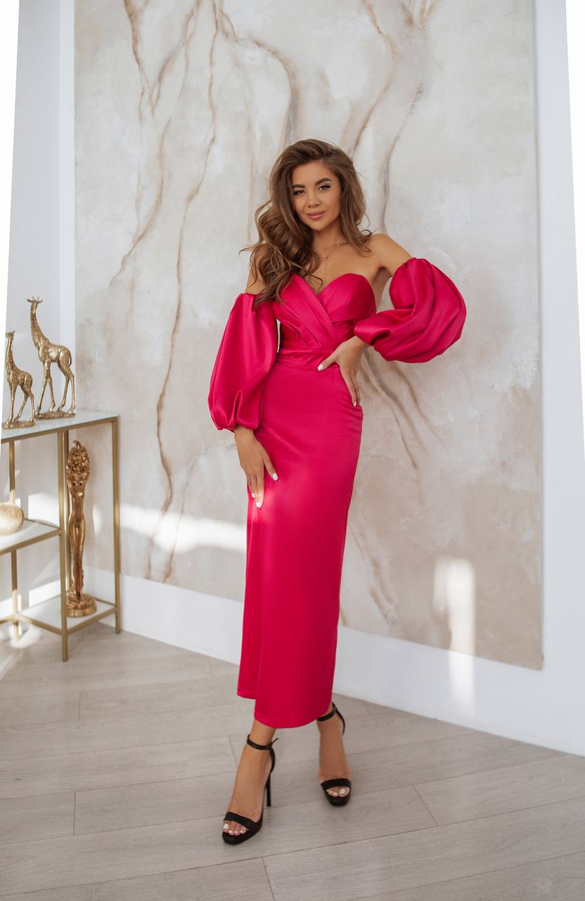 Woman in a bright pink dress standing against a marble wall.