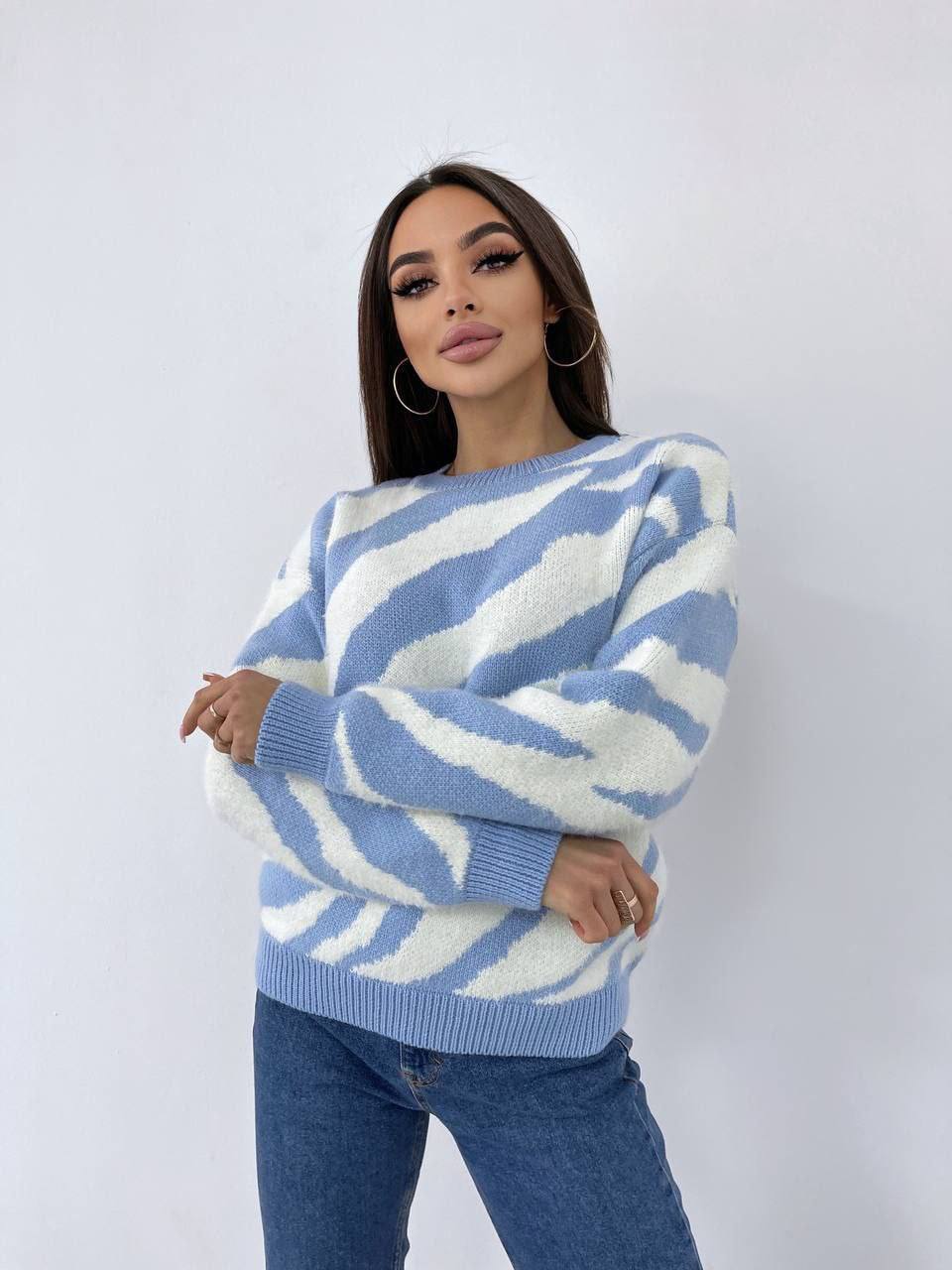 Woman wearing a blue and white patterned sweater against a plain background