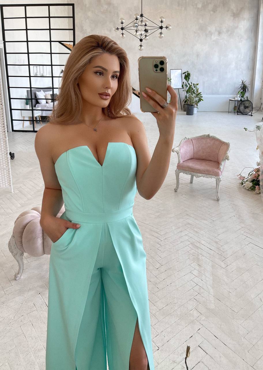 Woman in a strapless light blue dress taking a mirror selfie in an elegant room.