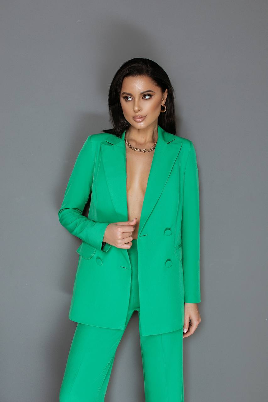 Woman wearing a green suit against a gray background