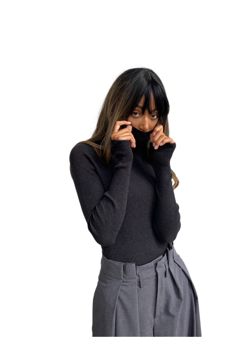 Woman wearing a black turtleneck sweater and gray pants on a white background
