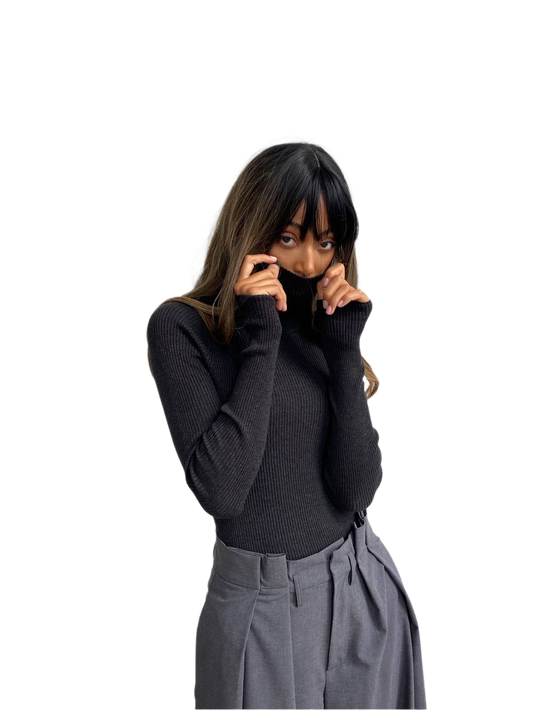 Woman wearing a black turtleneck sweater and gray pants on a white background