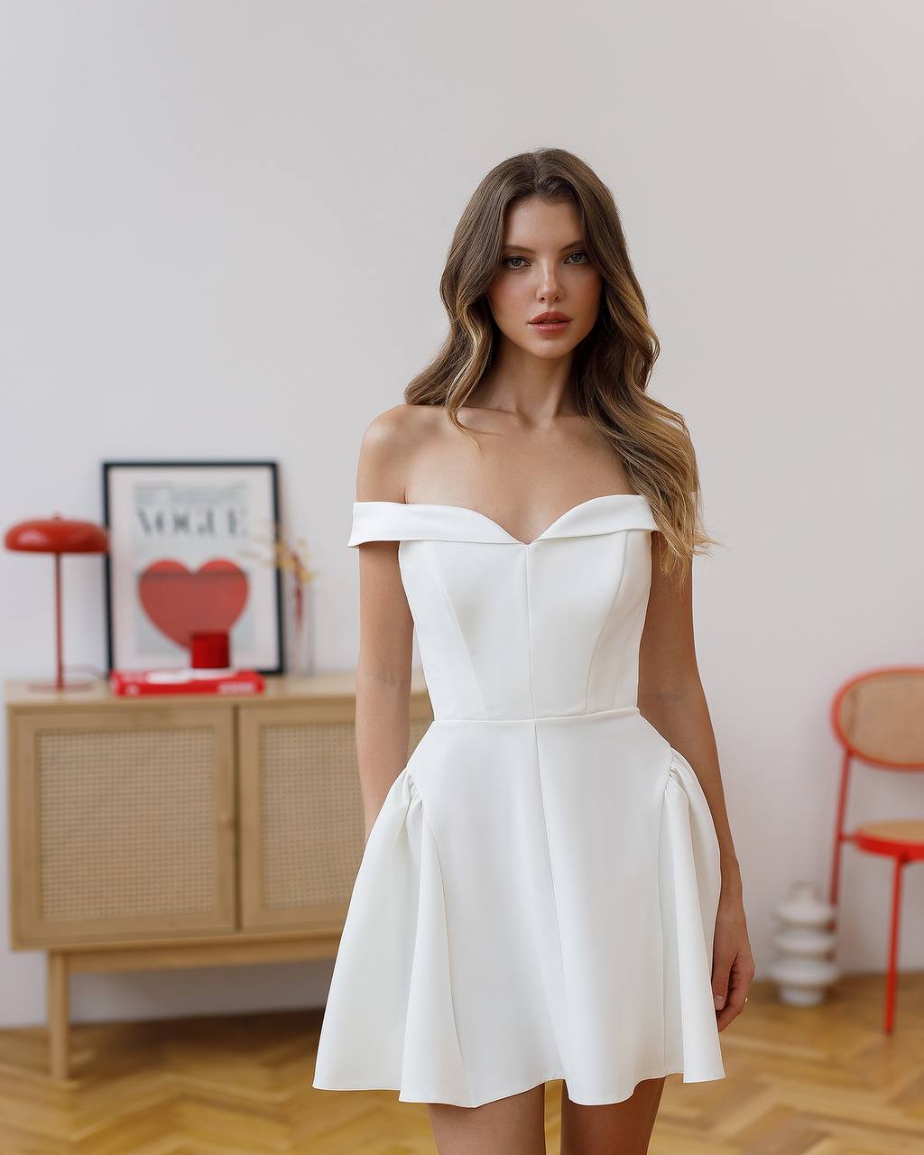 Woman wearing a white off-shoulder dress in an indoor setting.