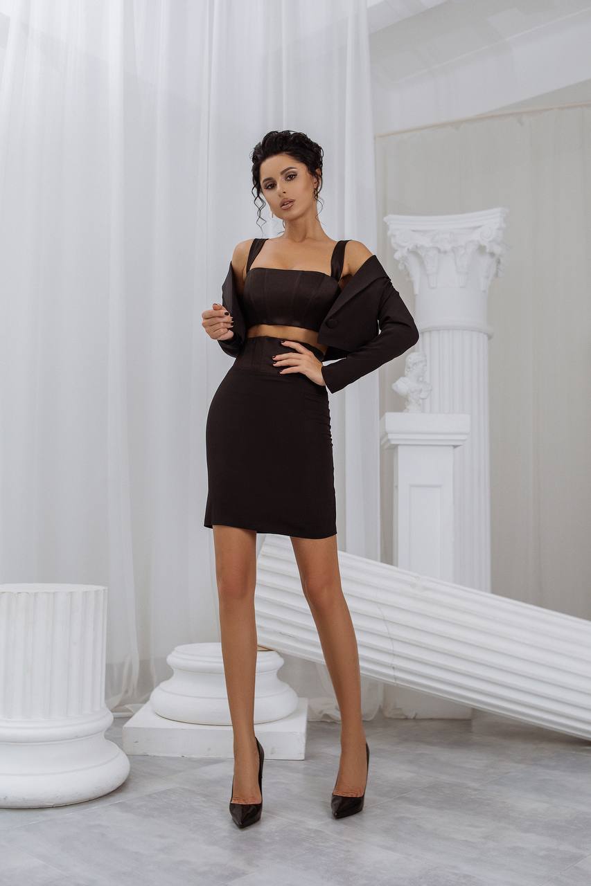 Woman in a black dress standing in a classical setting with white columns.