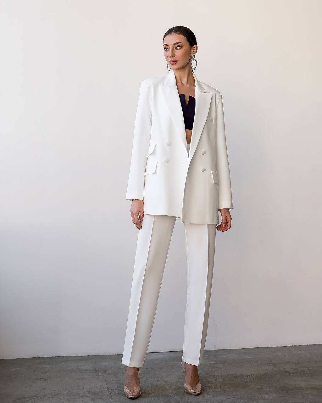 Woman wearing a white suit with a black top against a plain background