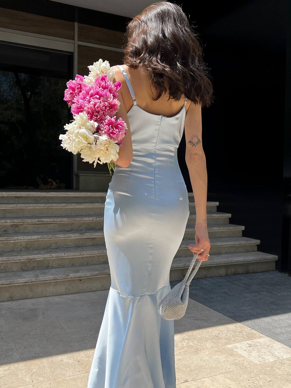 Woman in a white dress holding a bouquet of flowers outdoors.