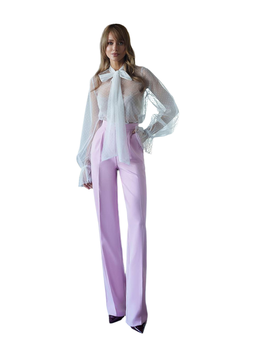 Woman wearing a white blouse with a bow and light purple pants on a white background