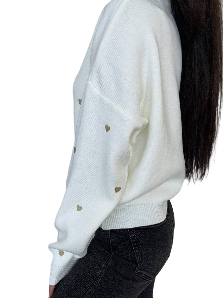 White sweater with gold heart patterns worn by a person on a white background