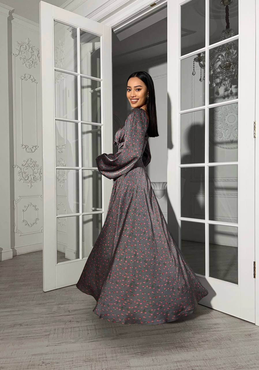 Woman in a long, dark-colored dress standing in a room with white French doors.