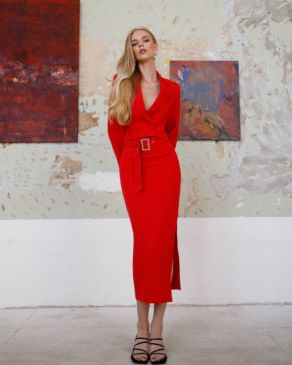 Woman in a red dress standing in an art gallery with abstract paintings on the wall.