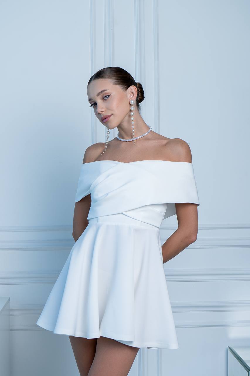 Woman wearing a white off-shoulder dress in an elegant interior setting