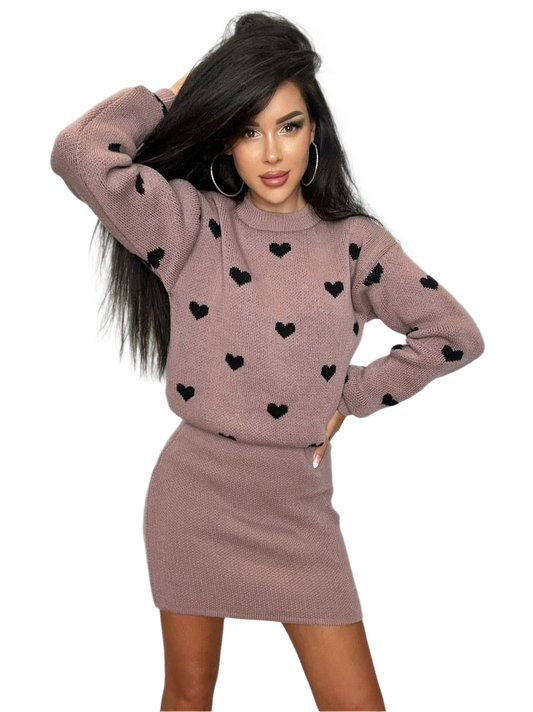 Woman wearing a mauve sweater with black heart patterns and matching skirt on a white background