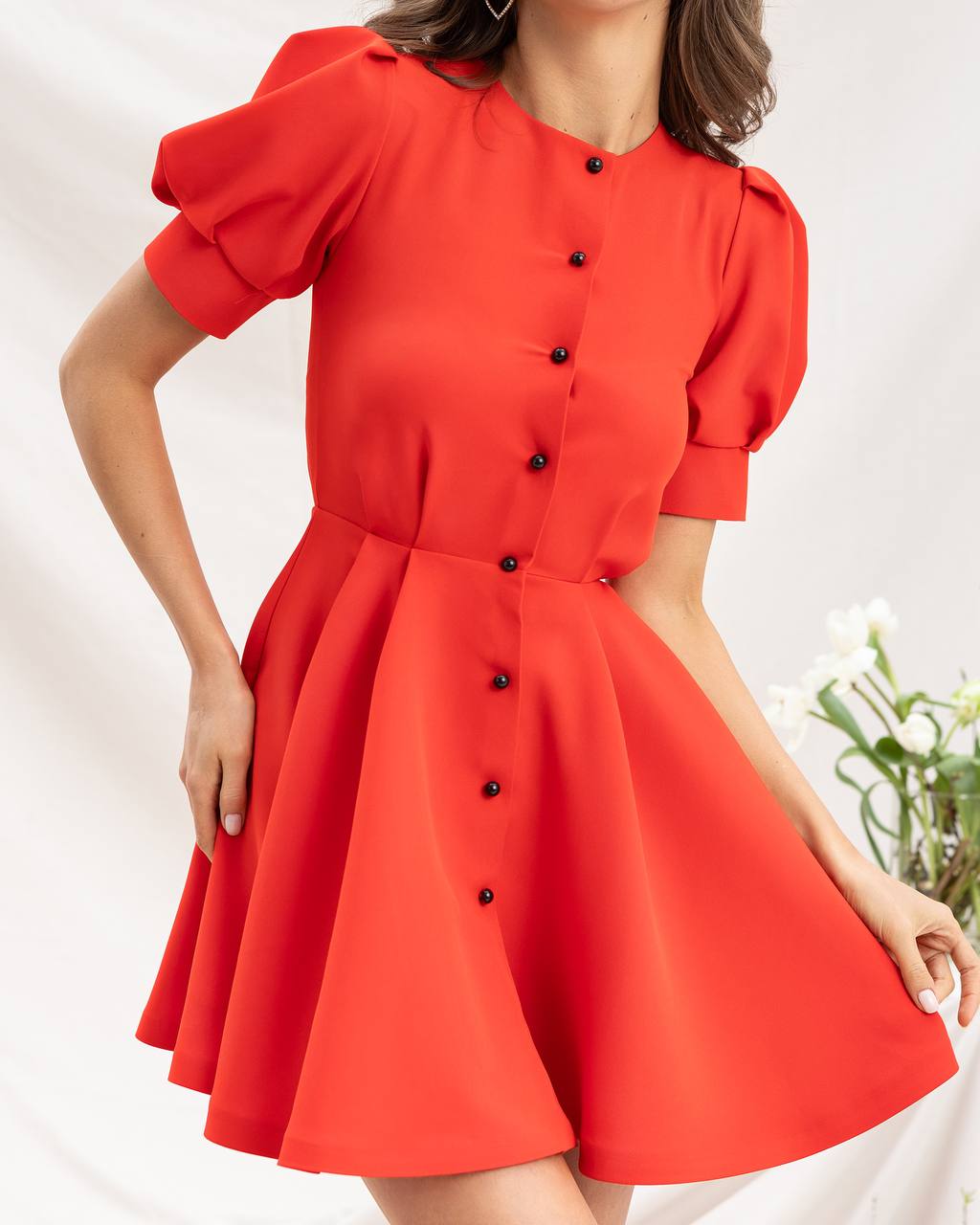 Red dress with black buttons worn by a person on a white background