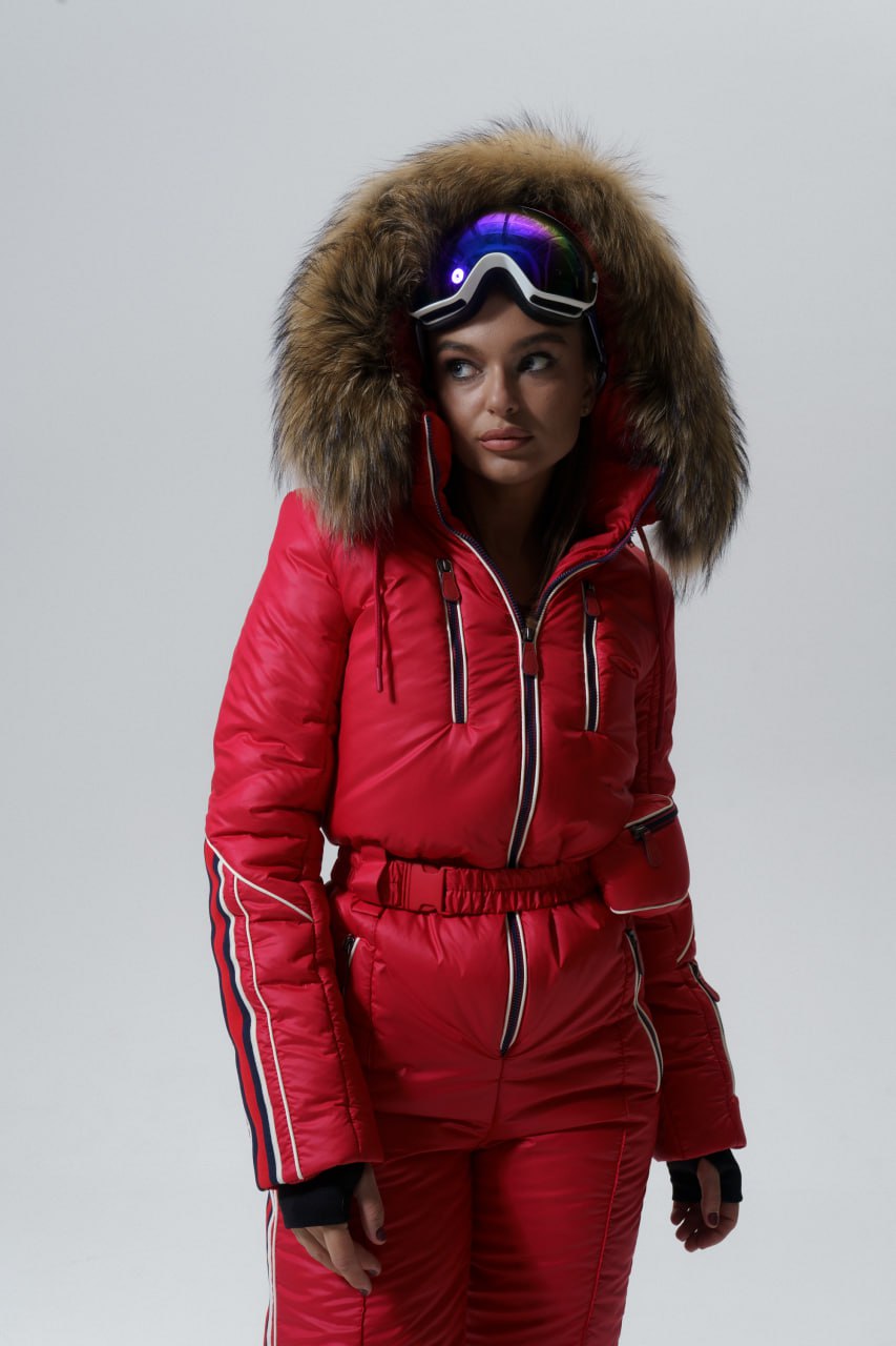 Person wearing a red ski suit with a fur-lined hood on a gray background