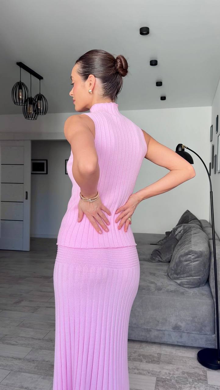 Woman in a pink dress standing in a modern living room.