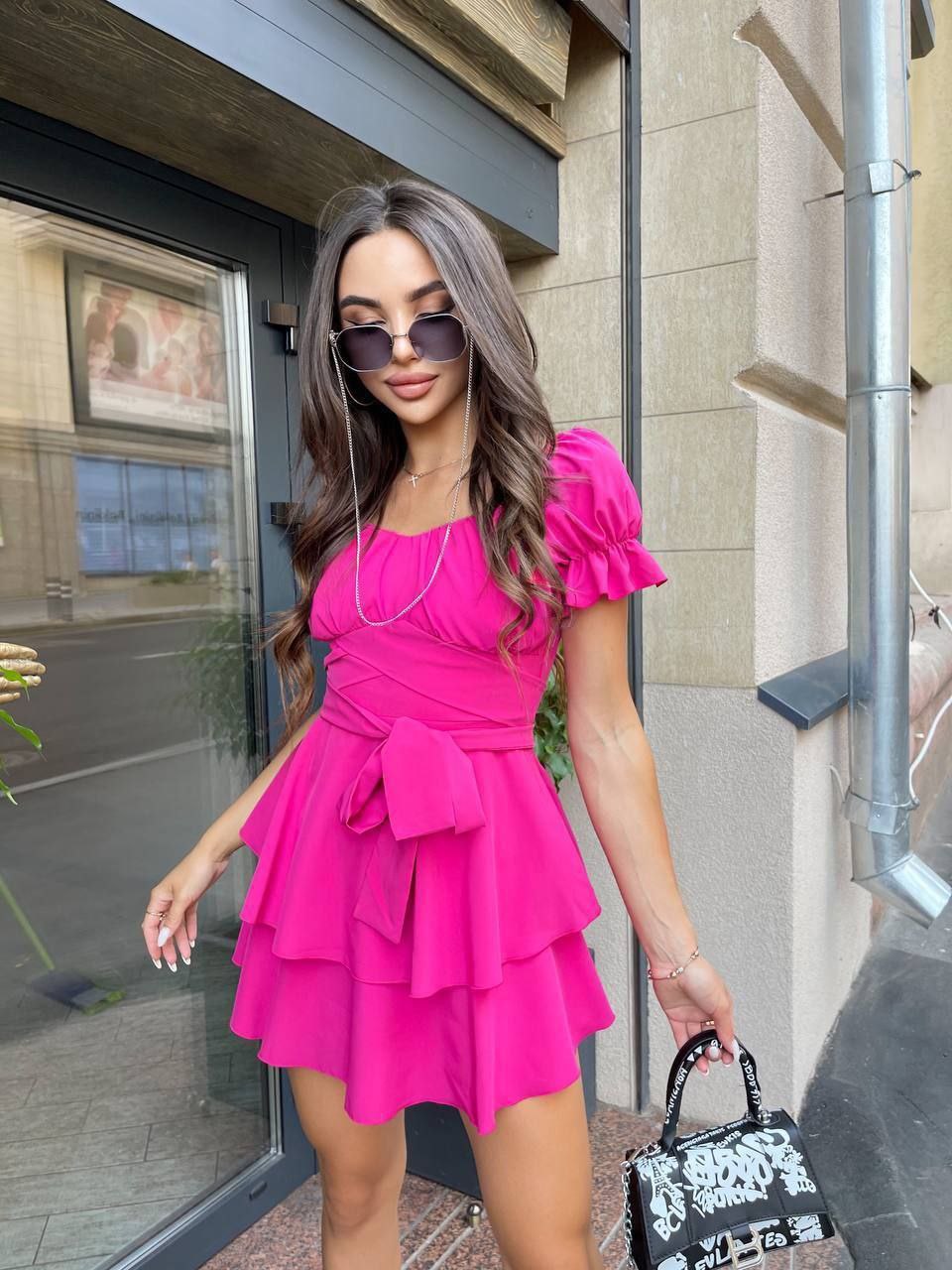Woman in a bright pink dress standing outside a building