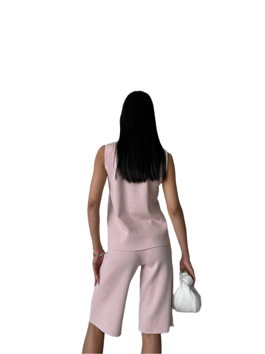 Woman wearing a pink sleeveless top and capri pants on a white background