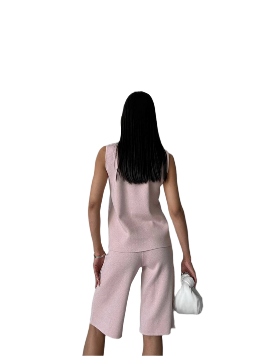 Woman wearing a pink sleeveless top and capri pants on a white background