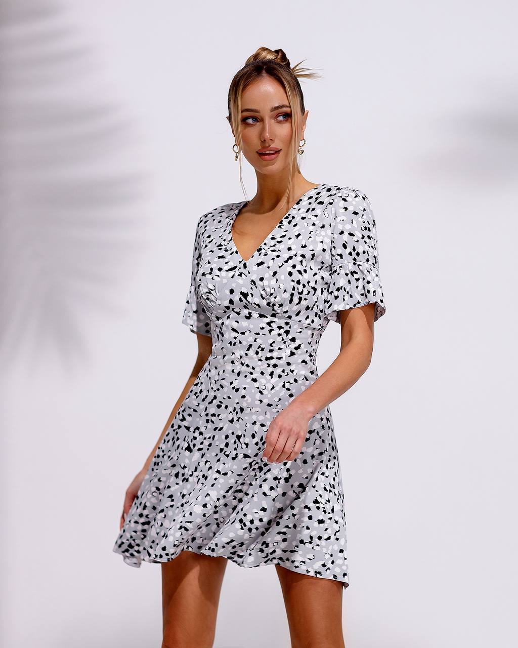 Woman wearing a black and white patterned dress against a plain background