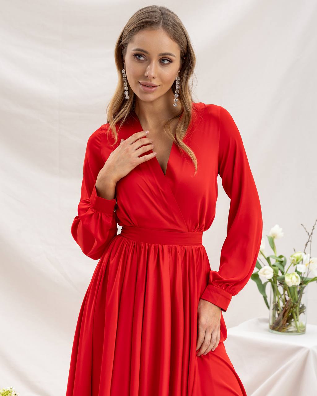 Woman wearing a red dress with long sleeves against a white background
